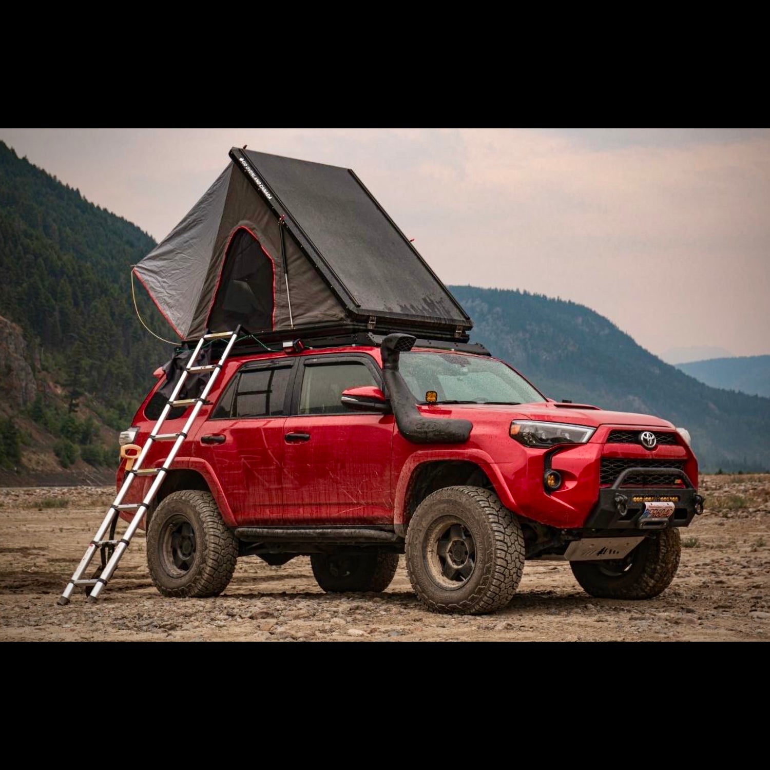 Red Toyota 4Runner with rooftop tent overland camping in forest