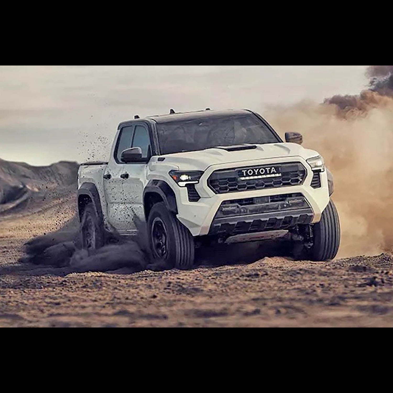 White Toyota Tacoma TRD spinning tires in the dirt