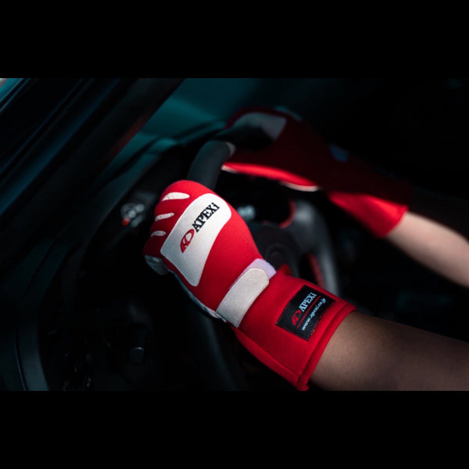 racing driver grabbing steering wheel with red racing gloves