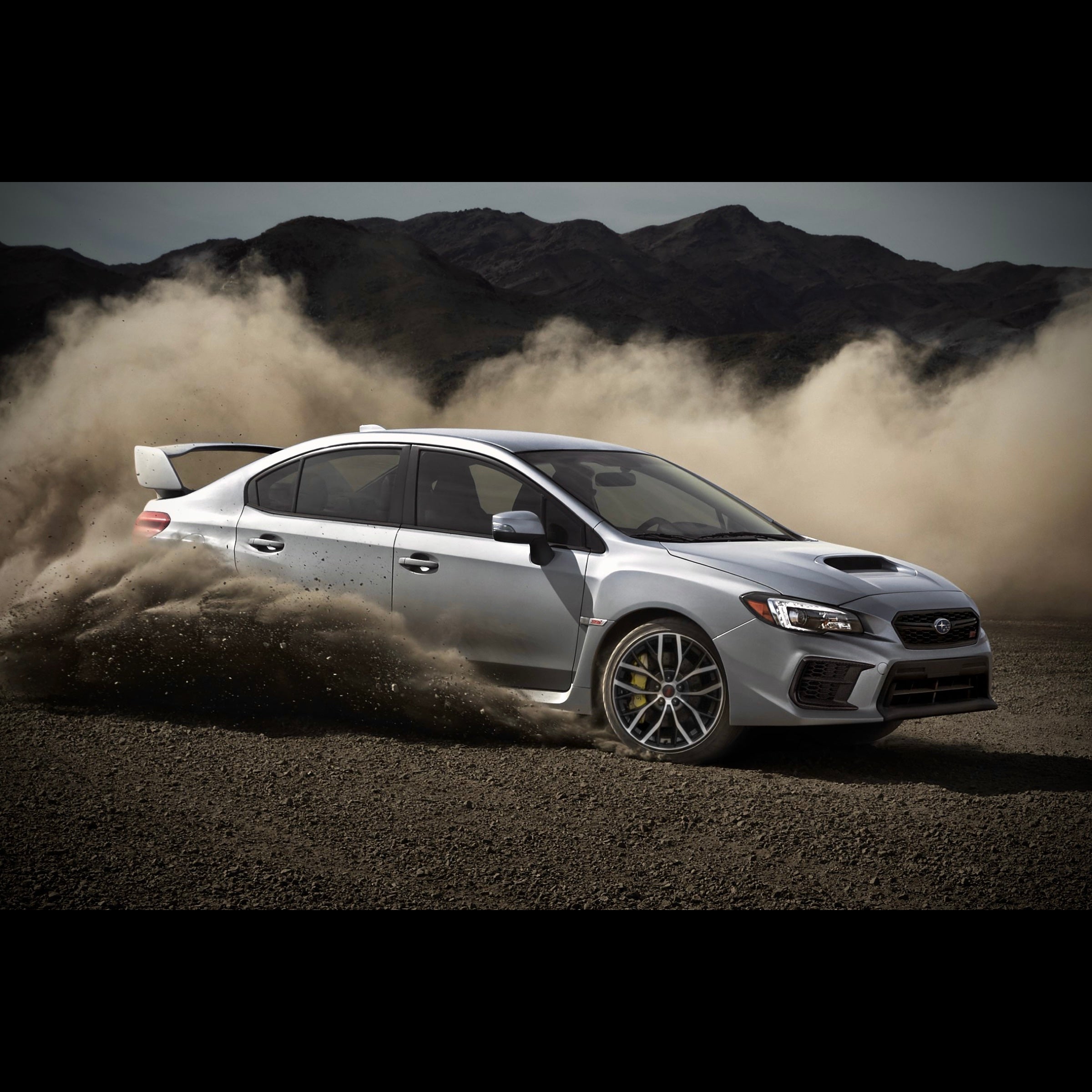 White Subaru WRX STI spinning tire in dirt